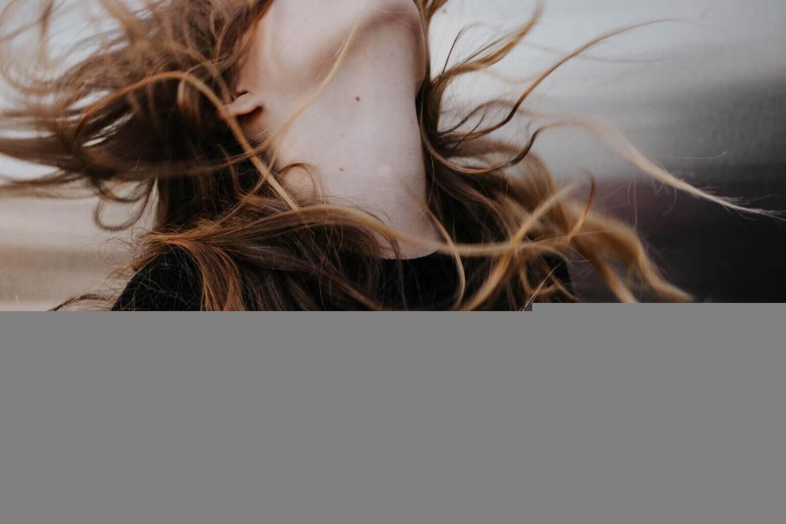 orange-haired woman wearing black top flipping head backwards