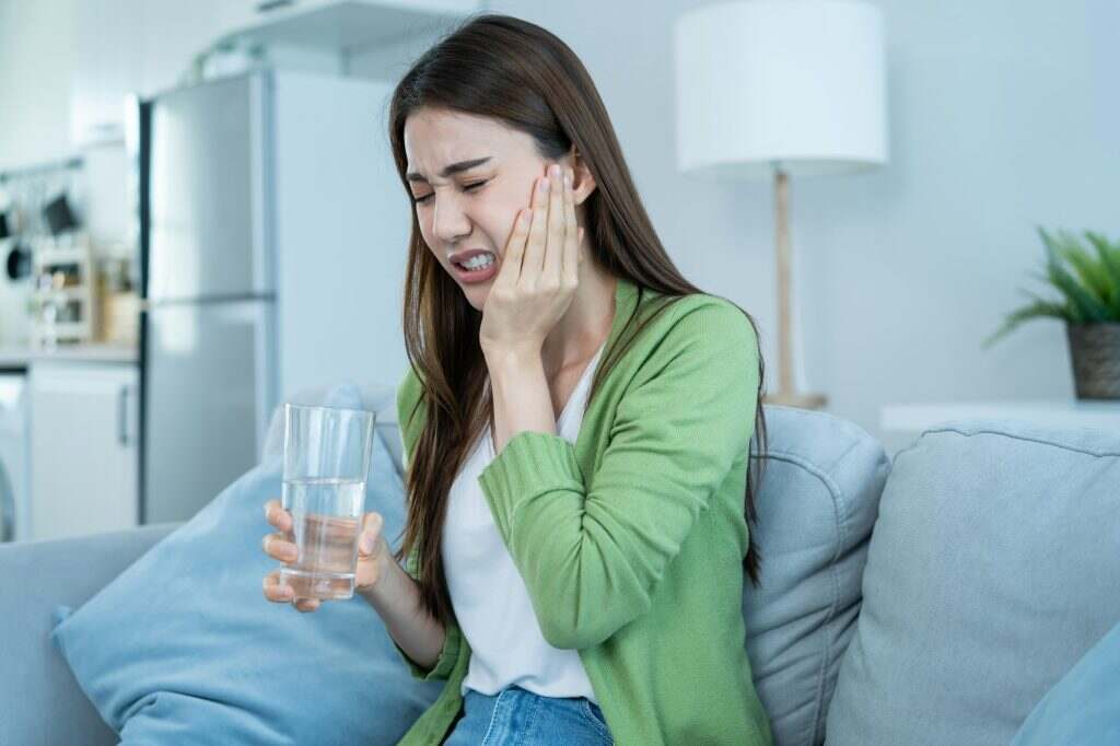 Asian beautiful woman feel terrible toothache after drink cold water.