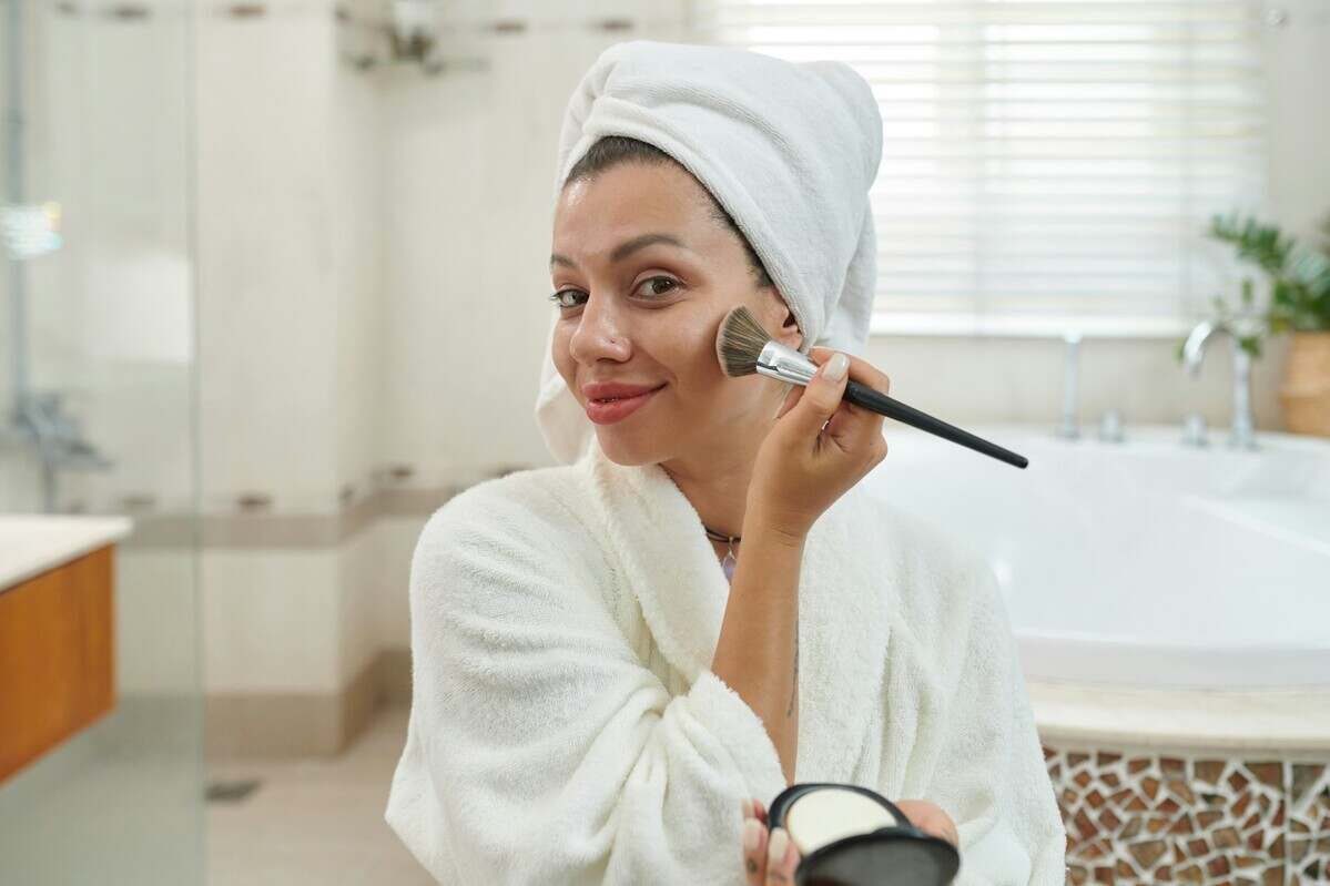 Happy young woman applying powder