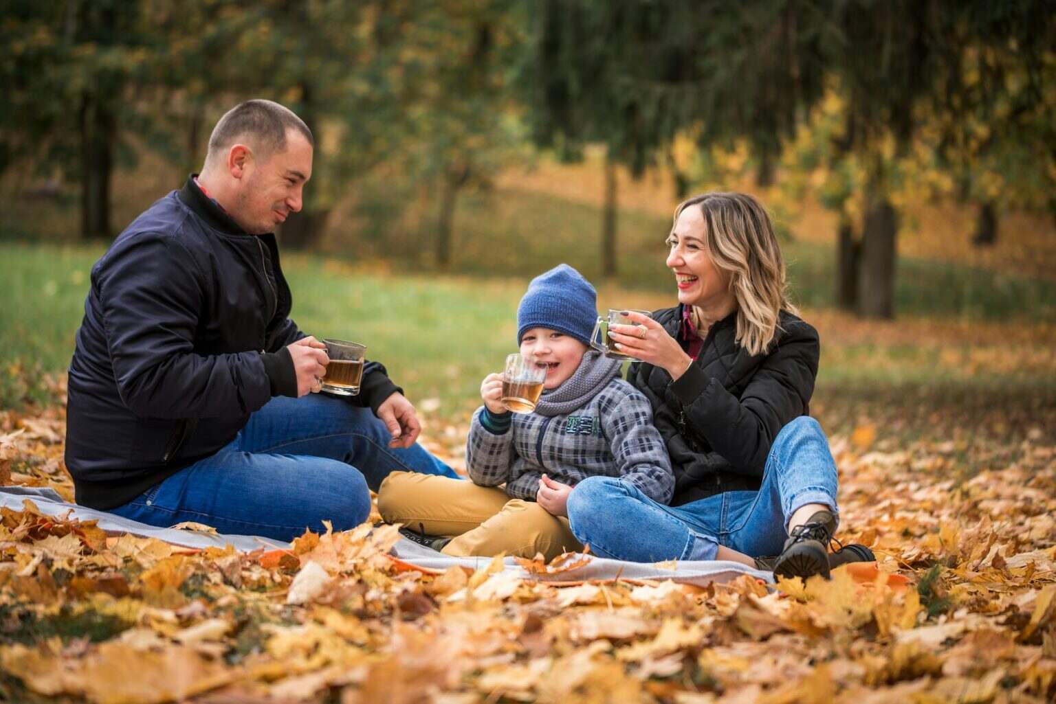 Mom, dad and son are actively playing in the park, laughing. Autumn, leaf fall. Cheerful happy famil