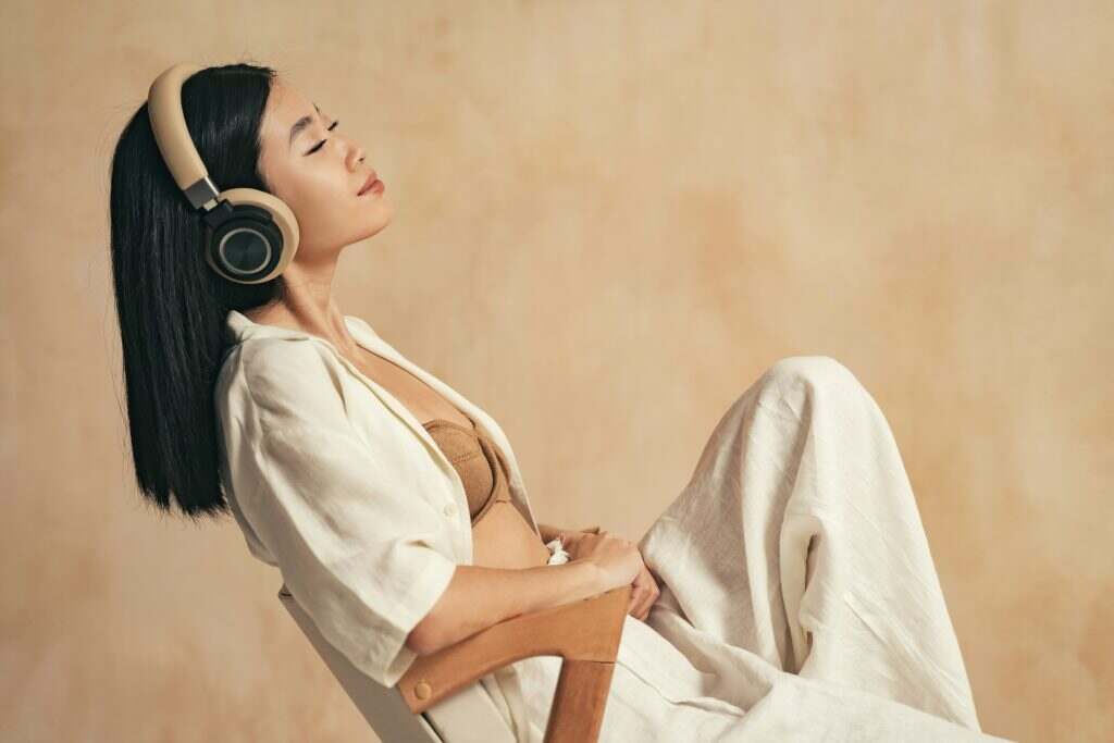 Profile view of asian female enjoying calm meditative sounds in her headphones with closed eyes