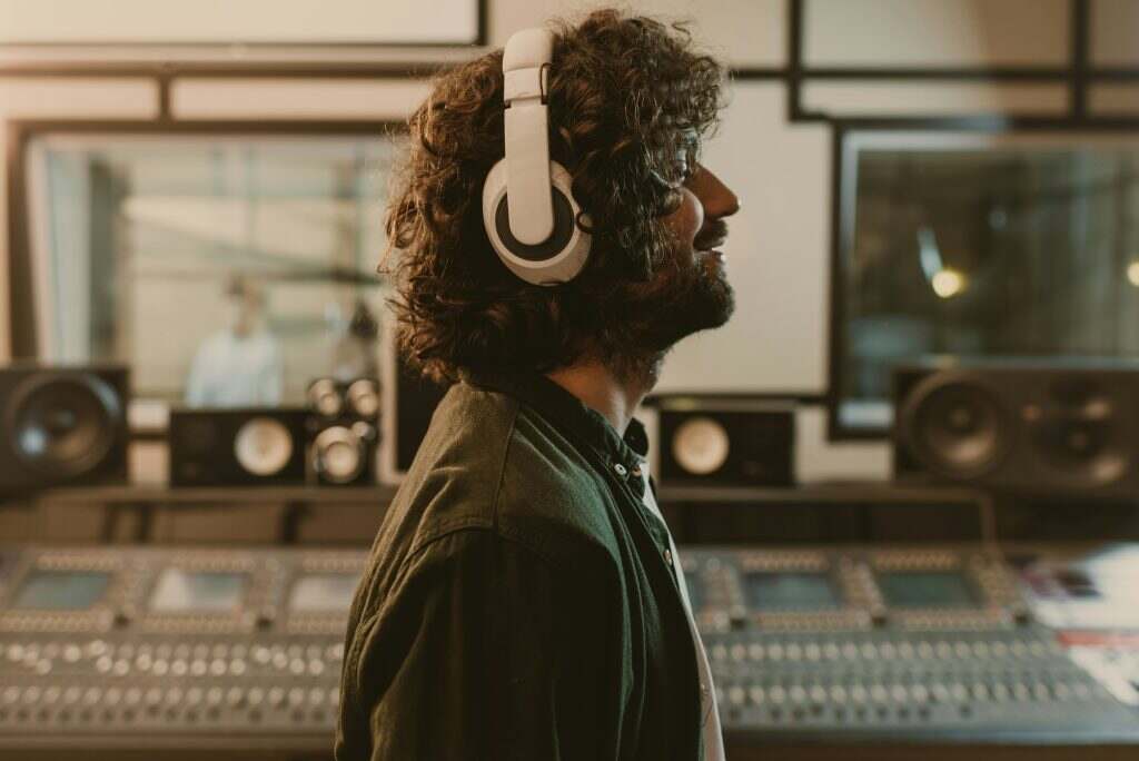 side view of sound producer in headphones enjoying music at studio