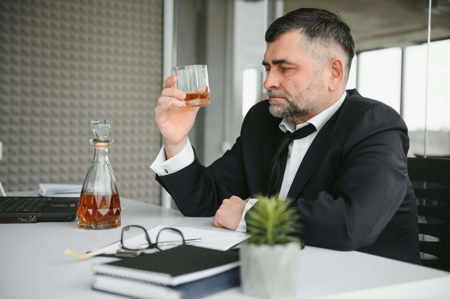 Old business man is drinking alchool at the office