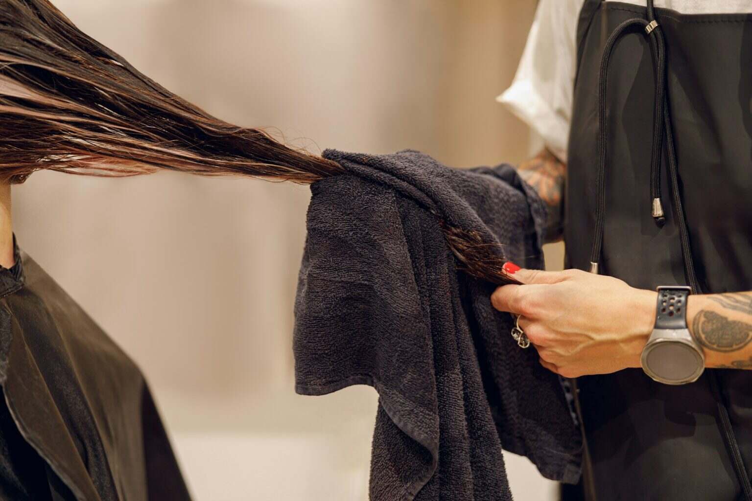 Close up of hairdresser is wrapping the wet hair of woman in towel after washing