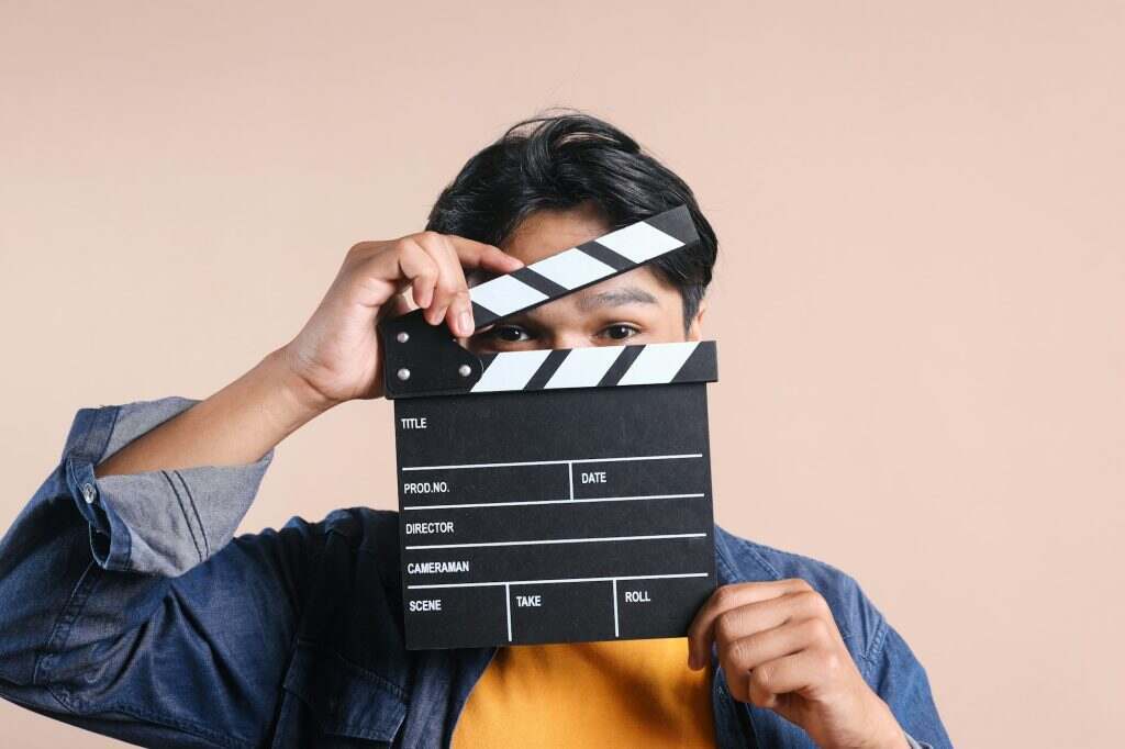 Young Man Peeking By Clapperboard. Movie Concept.