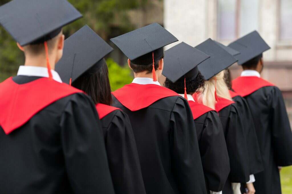 Comment s’habiller pour une remise de diplôme ? Back view of students in graduation costumes