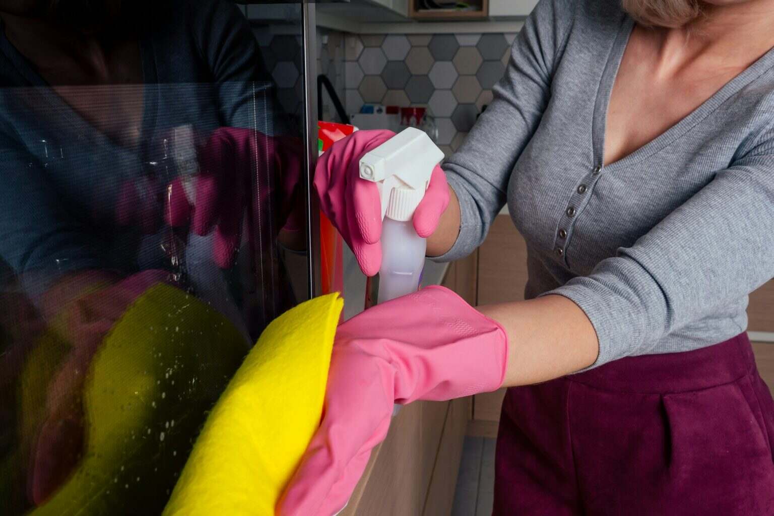 Young woman cleaning oven in the kitchen