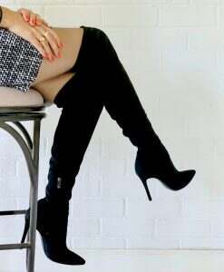 It’s boots time. Woman seating in stool wearing her black suede high heel boots & miniskirt