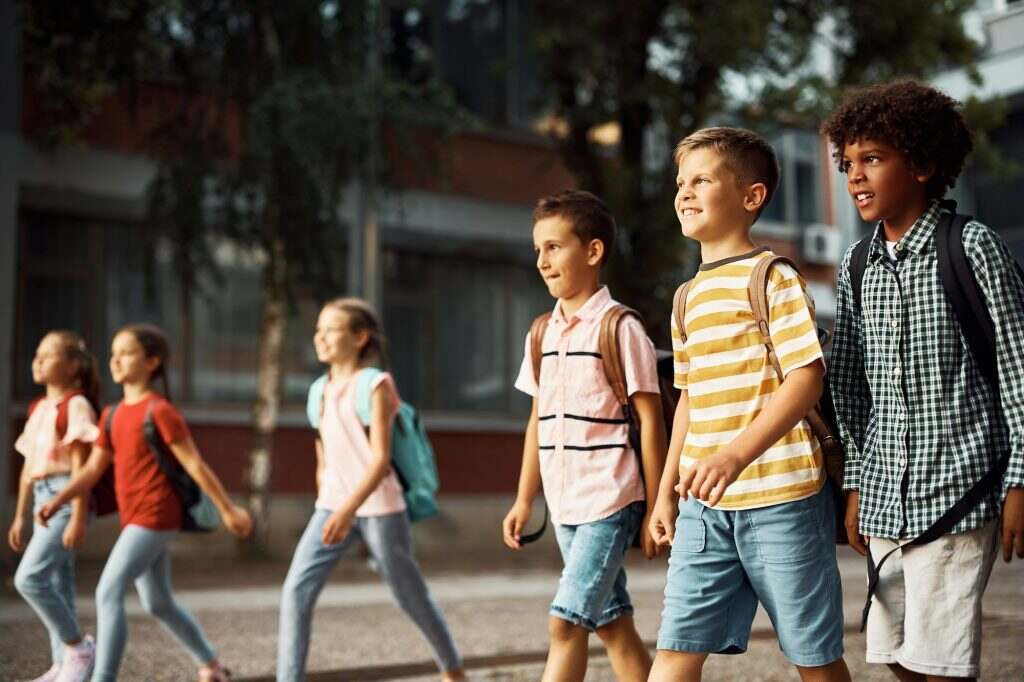 Multiracial group of happy elementary students coming to school.