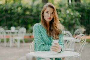 Outdoor shot of fashionable woman with long hair, dressed in green polkadot shirt