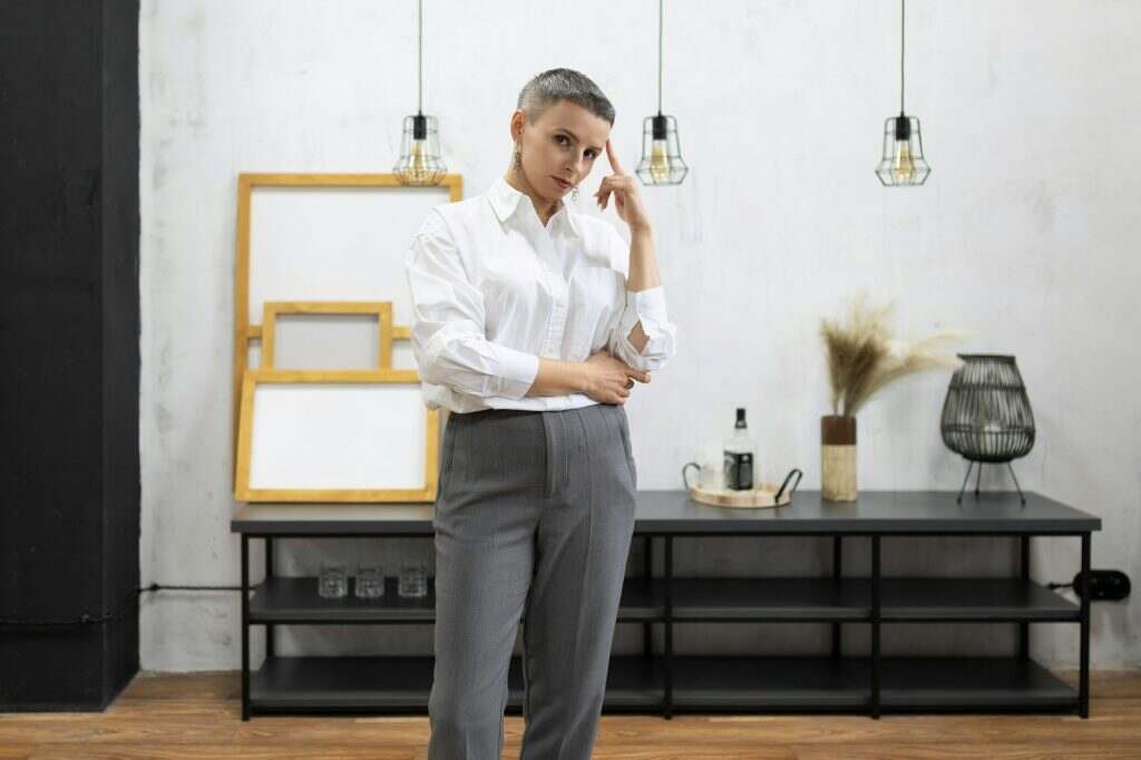 strong mature woman designer in white shirt and gray pants inside