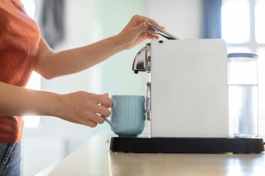Tout savoir sur le détartrage des machines à café Senseo Unrecognizable Woman Preparing Morning Coffee With Modern Machine In Kitchen
