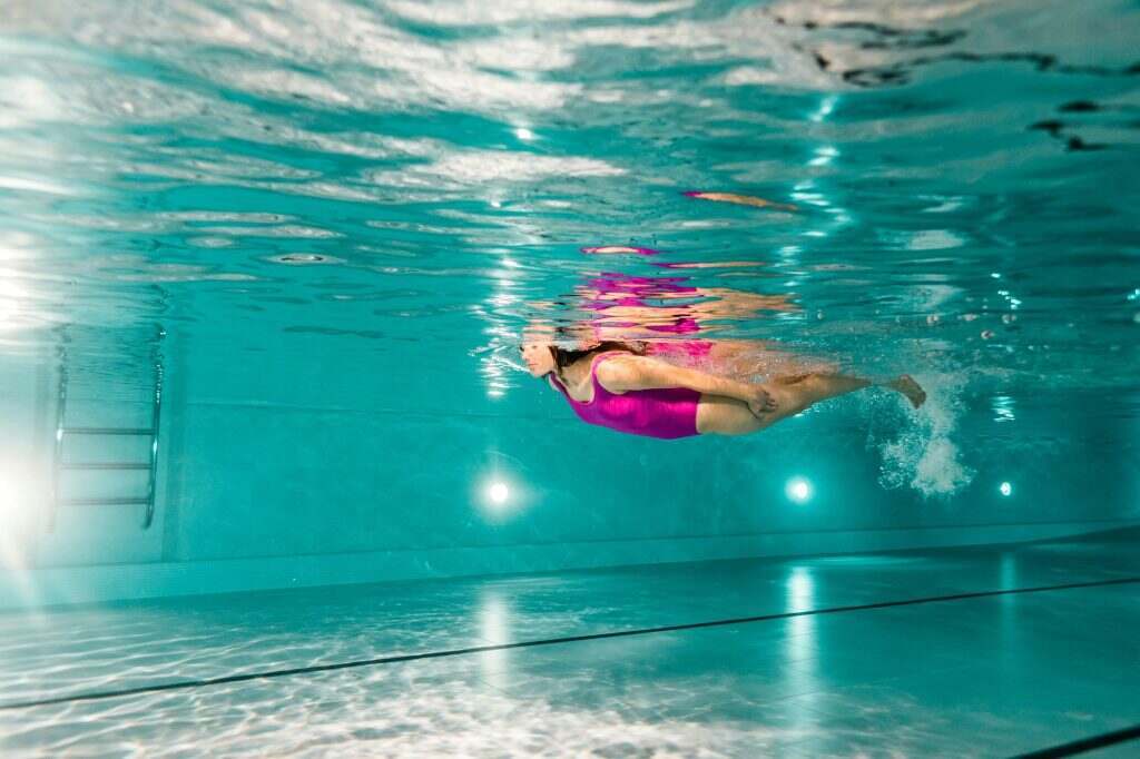 woman swimming in blue water in swimming pool