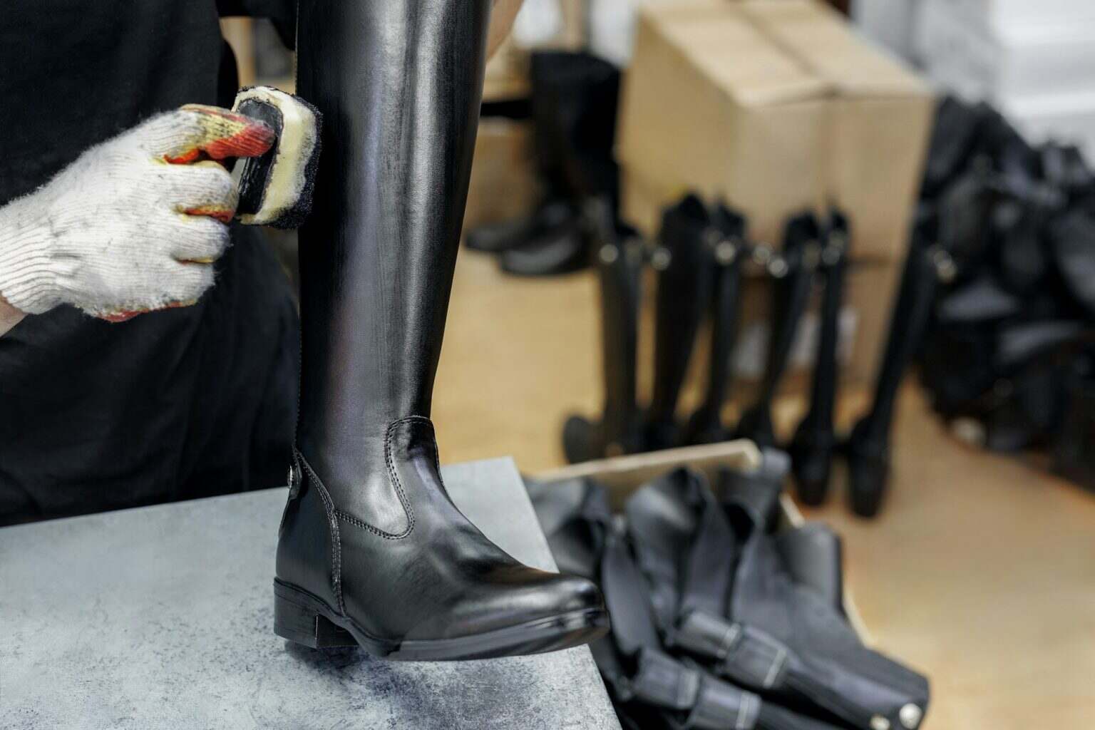 A shoemaker cleans leather boots in the workshop.