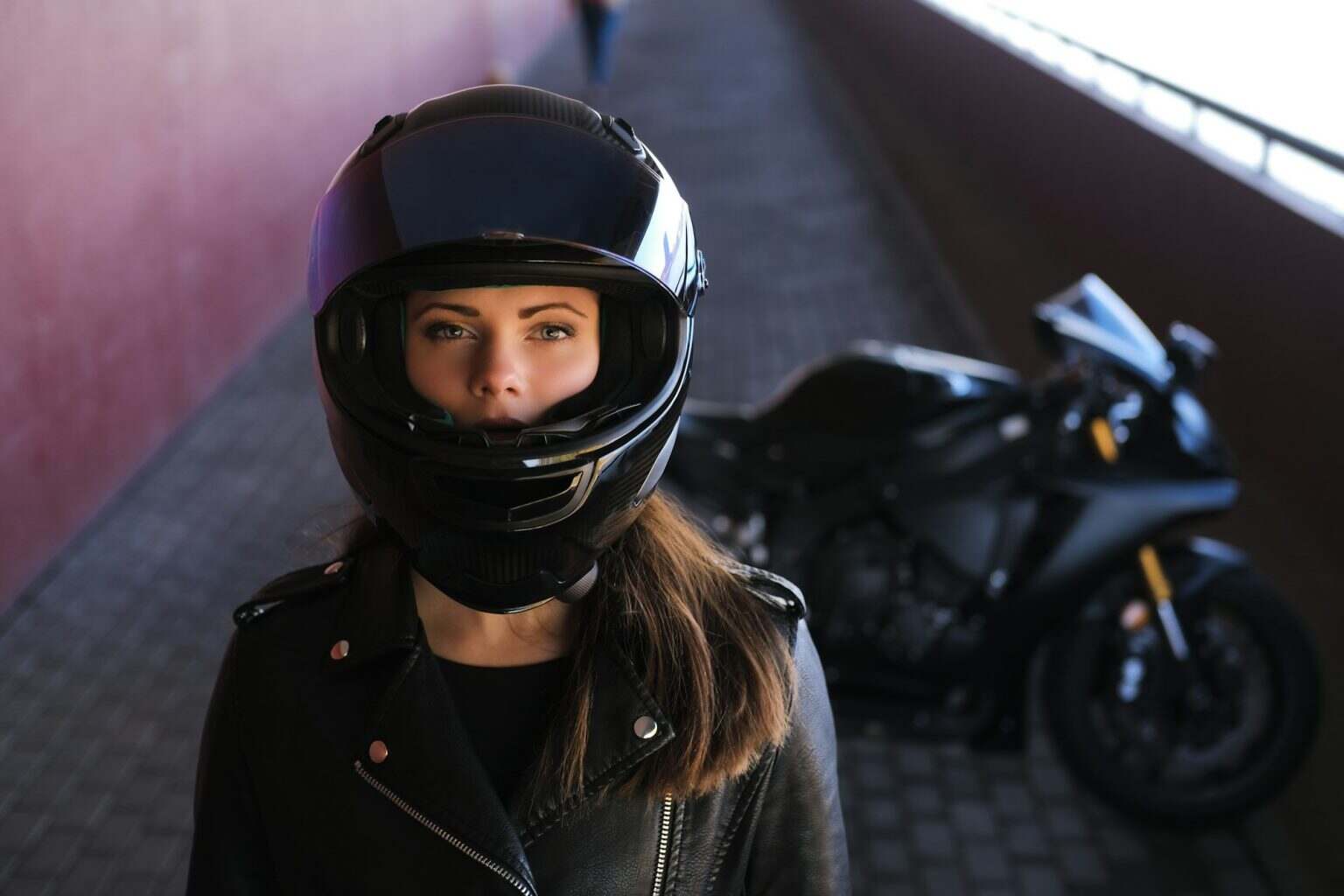 Attractive serious woman is standing next to her motobike