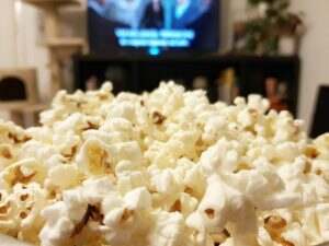 Close-up selective focus image of popcorn in front of tv.