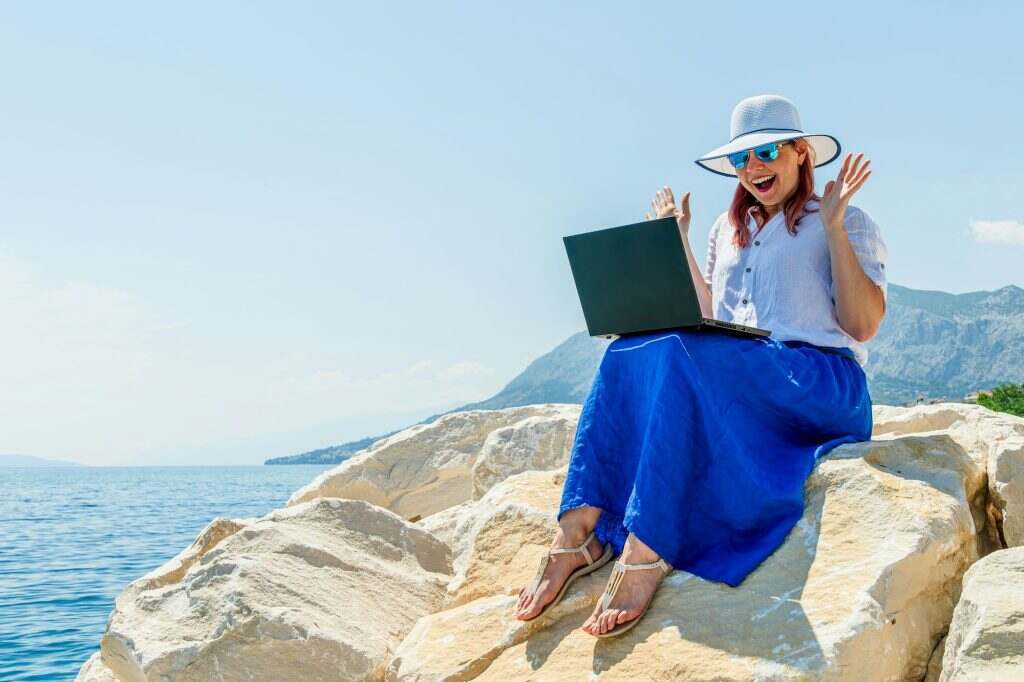 Female Freelancer Working on Computer During Vacation by the Sea