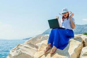 Female Freelancer Working on Computer During Vacation by the Sea