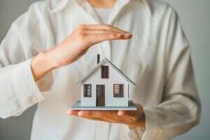 Hand protecting the icon house - the concept of insurance..
