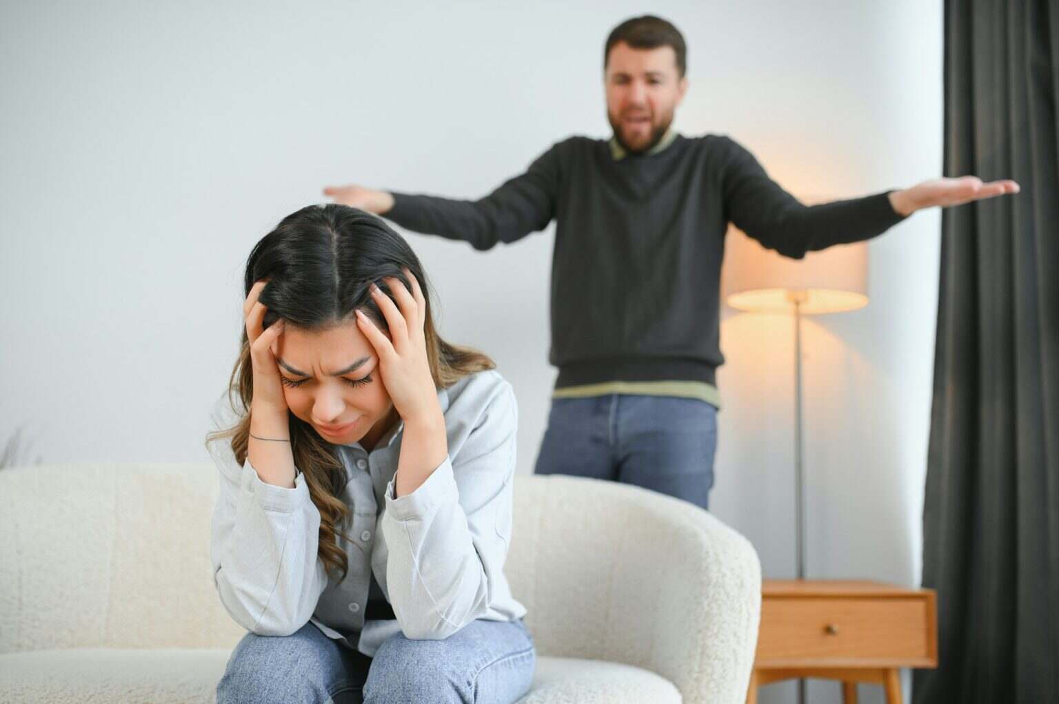 Irritated husband is shouting at his wife with violence. Woman is covering her face with fear