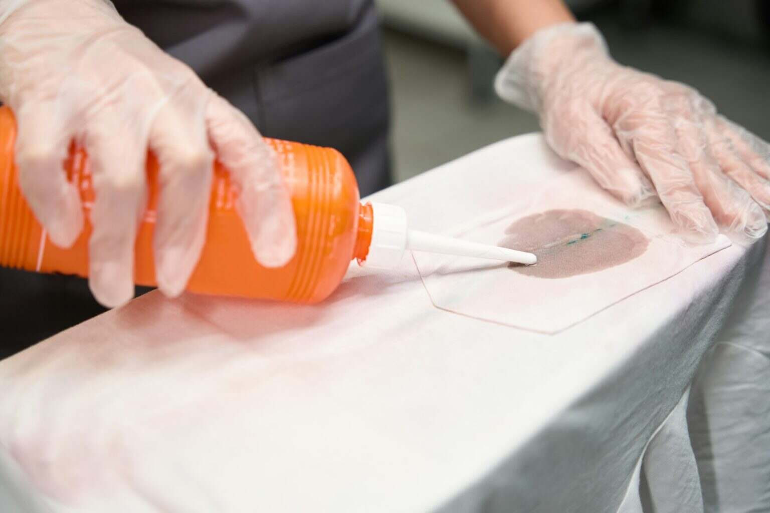Laundry worker treating dirty spots on clothes before dry cleaning