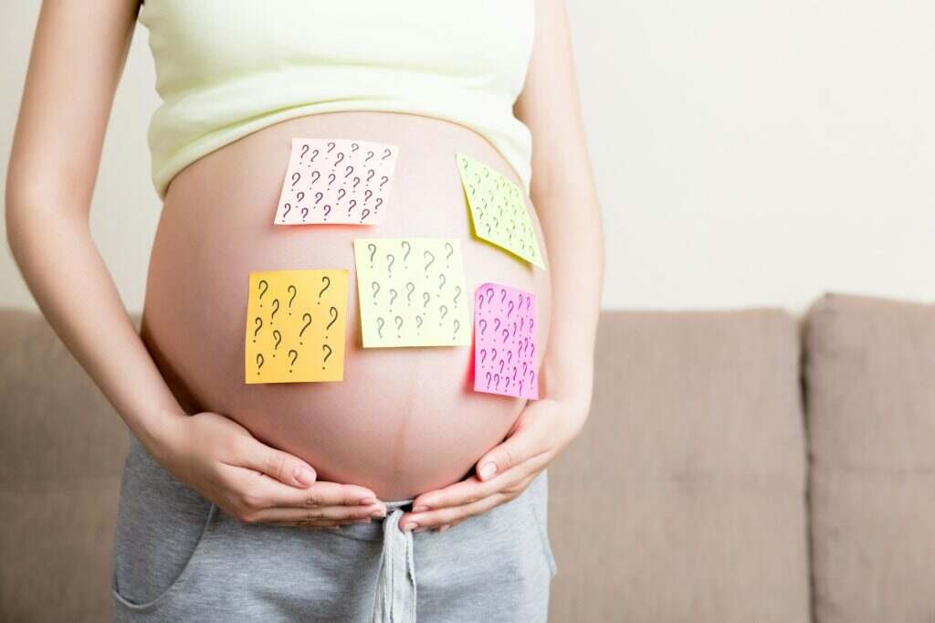 Pregnant woman belly with question mark. Pregnancy and thinking problem
