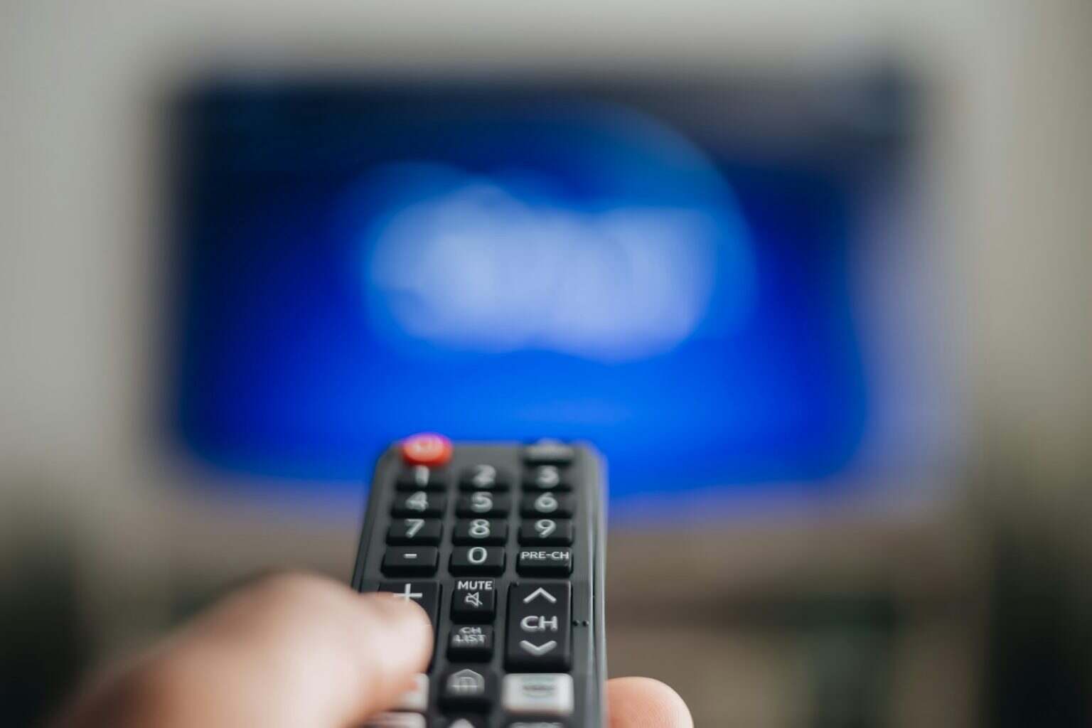 streaming services, African American man using remote to change what is being watch on television