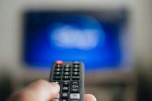 streaming services, African American man using remote to change what is being watch on television