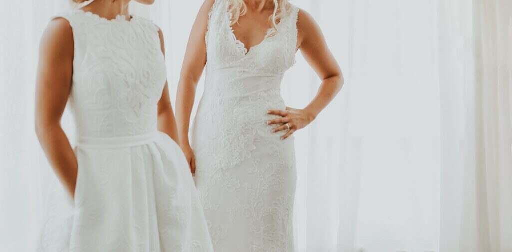 two gay women in wedding dresses hugging each other. focus to the dress. faceless