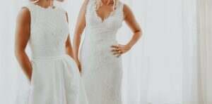 two gay women in wedding dresses hugging each other. focus to the dress. faceless