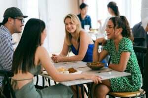 Happy people laughing enjoying meal having fun sitting together at restaurant table, diverse friends