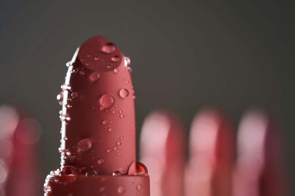 Red lipsticks with water drops on a dark background.