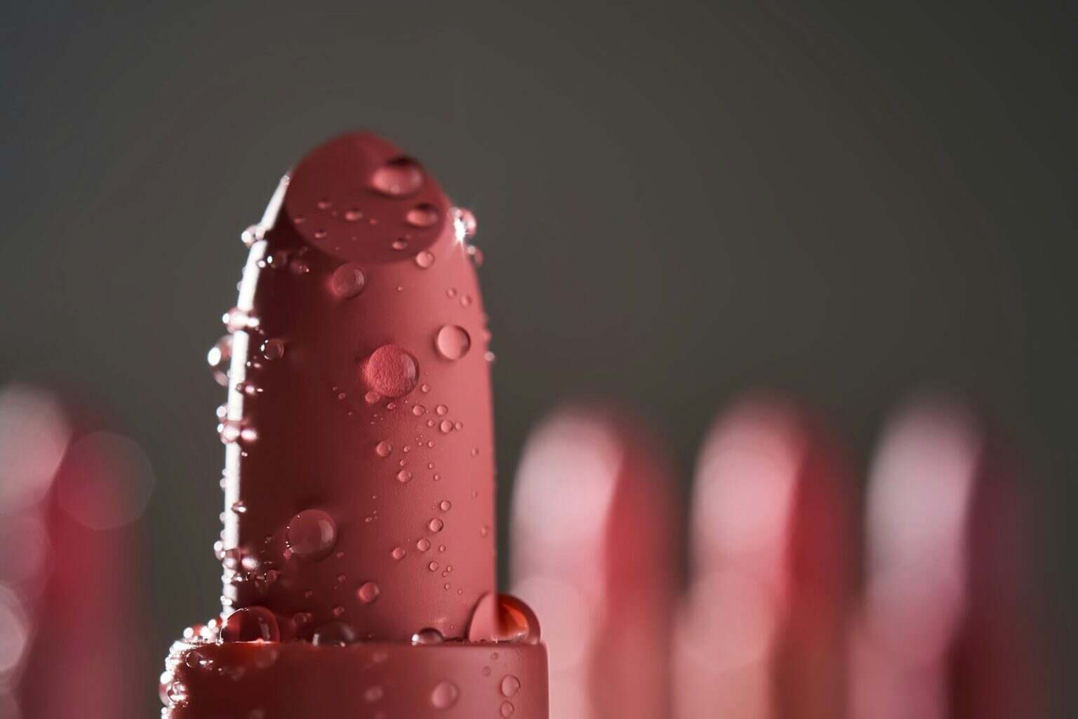 Red lipsticks with water drops on a dark background.