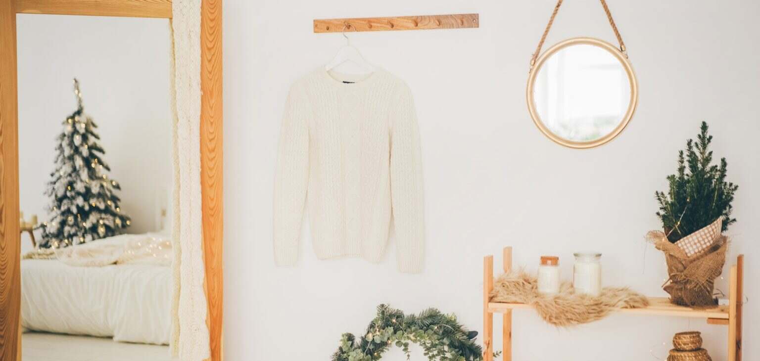 Scandinavian hallway interior with big mirror and shoe storage bench near white wall.