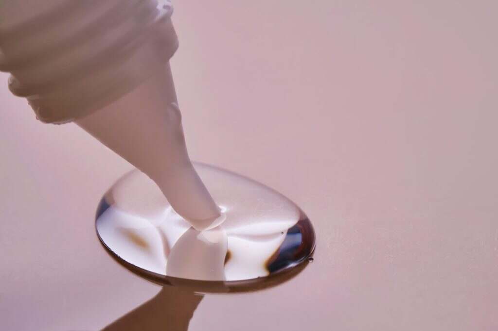 Stationery glue flows onto pink paper.