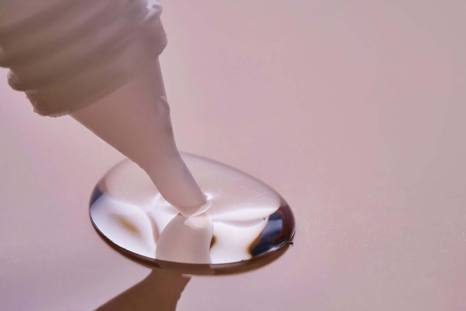 Stationery glue flows onto pink paper.