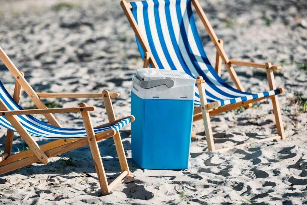 striped beach chairs and cooler on sand