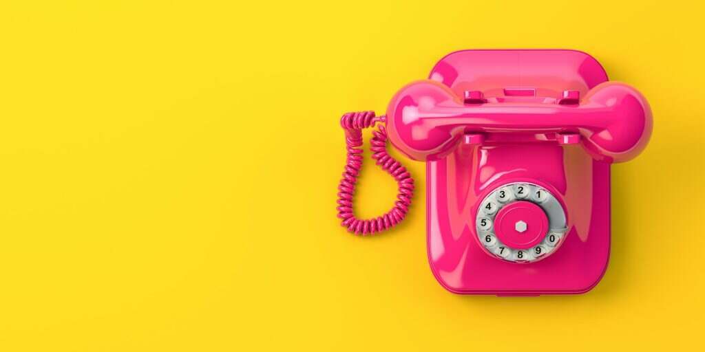 Vintage pink telephone on yellow background.
