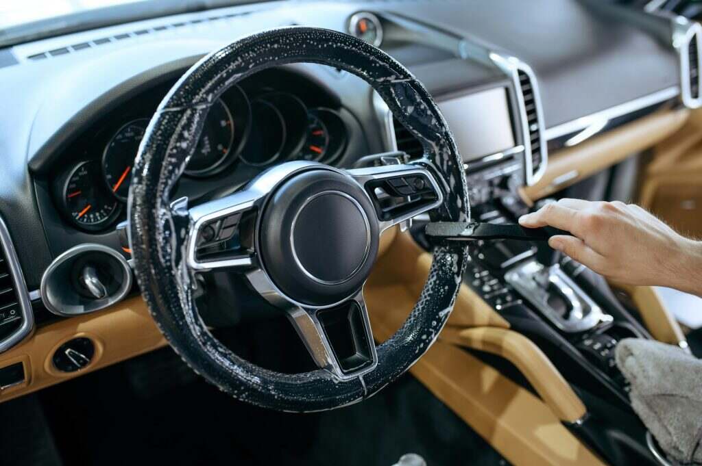 Worker wipes car steering wheel, detailing