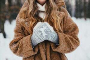 Young woman in fur coat, gloves and scarf in snowy forest