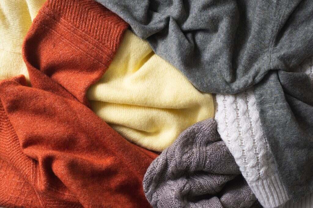 Autumn or winter background with warm sweaters. Pile of knitted clothes.