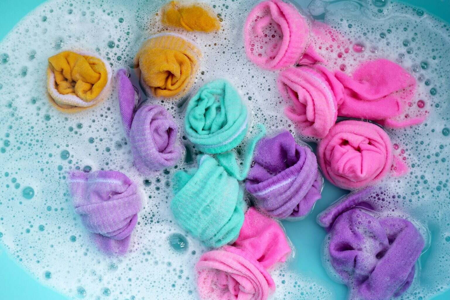 Dirty socks soaked in water, dissolving detergent in basin.