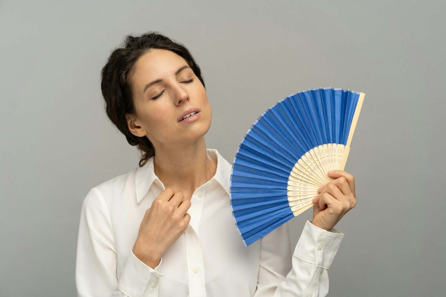 Overheated woman employee using wave fan suffer from heat sweating, closed eyes