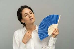 Overheated woman employee using wave fan suffer from heat sweating, closed eyes