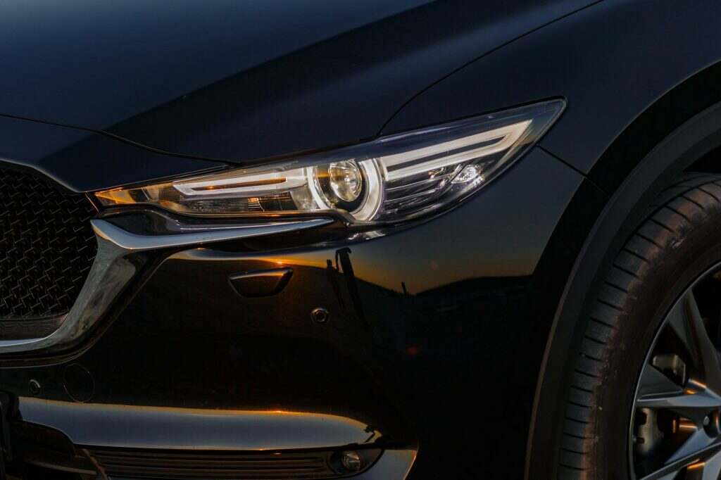 Part of the body of a black car at sunset