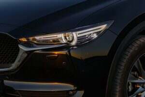 Part of the body of a black car at sunset