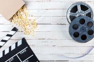 Top view of film reels, popcorn and movie clapper on wooden table, Movie time concept