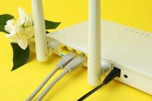 Wi-Fi router and flowers on yellow background