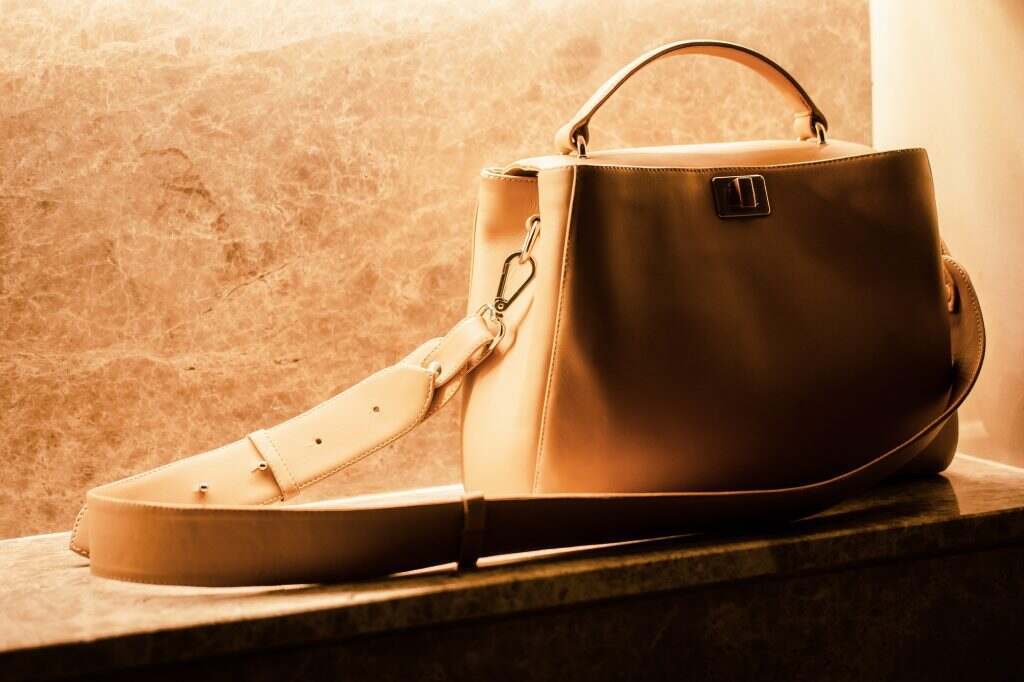Woman’s beige handbag on marble. Fashion blog concept. Copy space