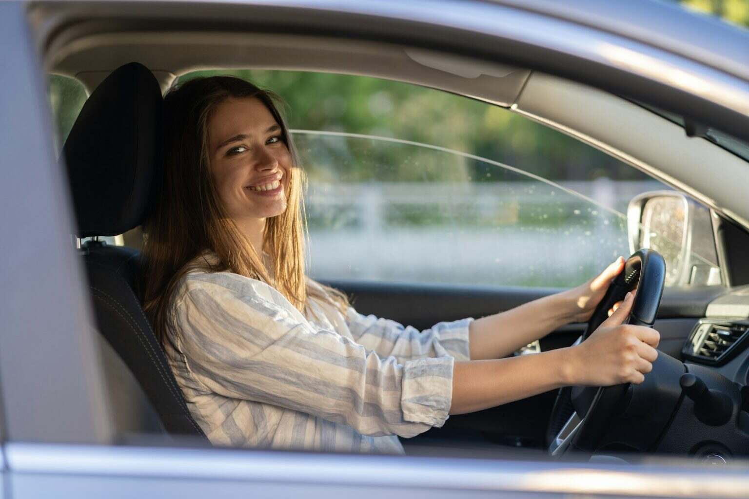 Young girl sit at driver seat in new car smiling hold hands on wheel happy to get driver license